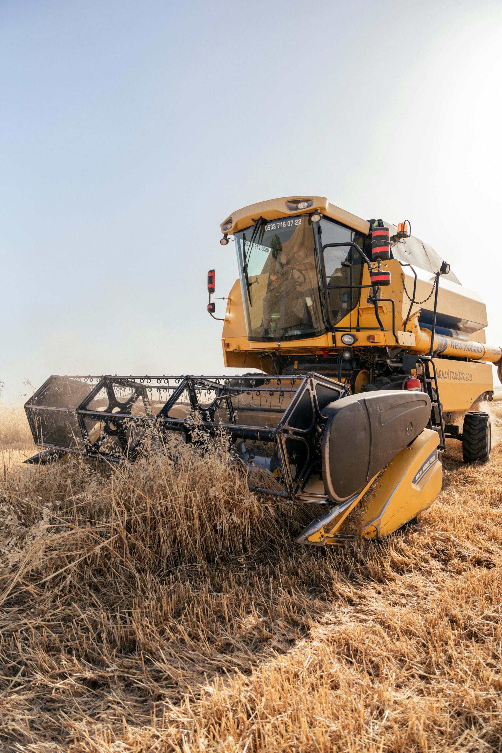A yellow combine harvester efficiently cuts and gathers wheat in a sunny rural field.